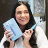 Frau mit Power LED Bleaching Schallzahnbürste von Diamond Smile in der Hand im Bad