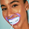 Kobieta wybiela zęby nakładką LED Diamond Smile, korzystając z telefonu, zabieg trwa 10 minut